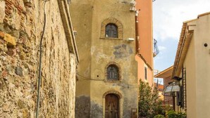 A narrow cobblestone street with a stone wall on one side and a building with a wooden door and arched windows. - La Casa di Elvira - Sea View (Giardini Naxos)