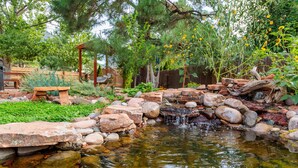 A garden with a small pond, rocks, and a wooden bridge.