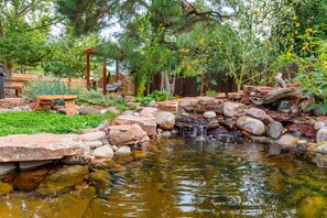 A garden with a small pond, rocks, and a wooden bridge.