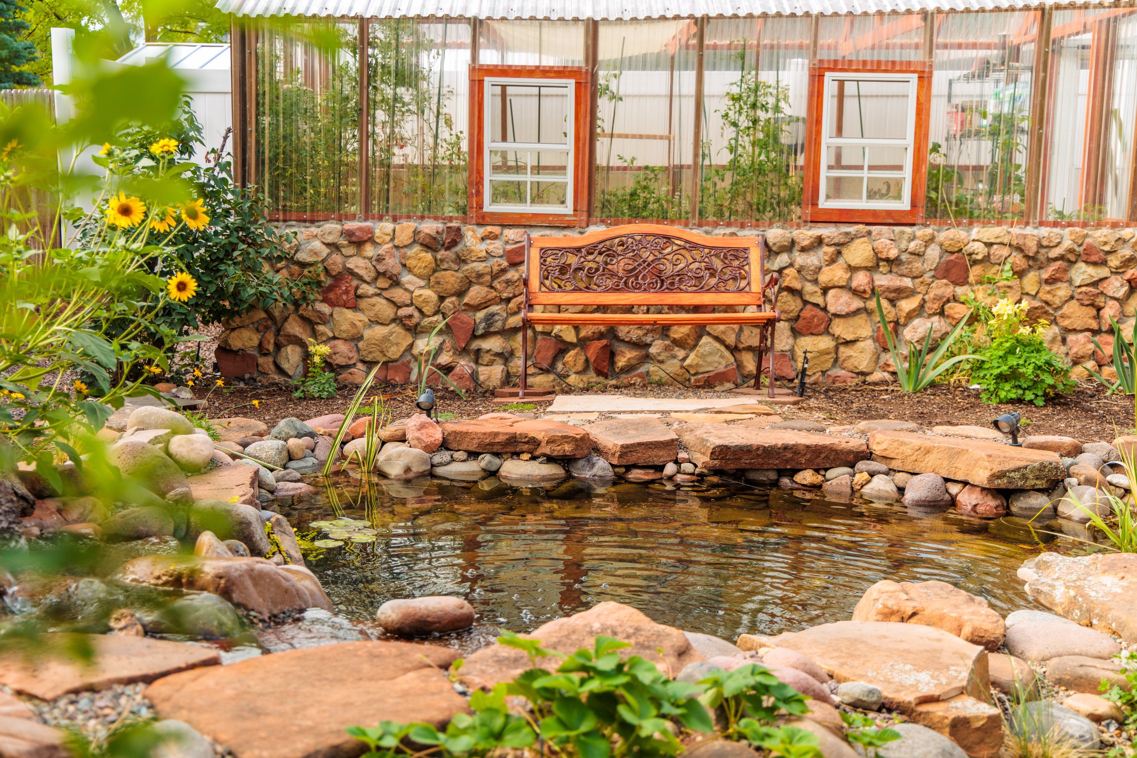 Paredes de pedra com um banco e um pequeno lago.