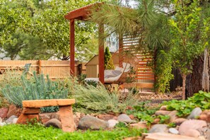 A garden with a wooden pergola, a wicker chair, a wooden bench, and a small wooden structure. - World Traveler's - Phenomenal Getaway Retreat with Spacious Backyard Paradise to Enjoy! (Flagstaff)