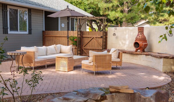 An outdoor patio with wicker furniture, a wooden fence, and a potted plant.