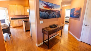 A modern kitchen with wooden cabinets, a stainless steel refrigerator, and a dining area with a table and chairs.