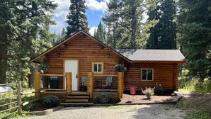 A log cabin with a porch, a door, and windows. - Cozy and Rustic "Bear Themed" Cabin~private pond and 7 miles to YNP entrance! (West Yellowstone)