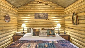 A log cabin bedroom with a bed, two nightstands, and a wall-mounted lamp. - Cozy and Rustic "Bear Themed" Cabin~private pond and 7 miles to YNP entrance! (West Yellowstone)