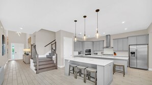 A spacious kitchen with a central island, stainless steel appliances, and a modern light fixture. - Paradise at Bear's Den | 6-Bed Villa w/ Loft, Games Room, and Private Pool (Kissimmee)