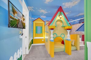 A children's play area with a slide, a small playhouse, and a TV mounted on the wall. - Paradise at Bear's Den | 6-Bed Villa w/ Loft, Games Room, and Private Pool (Kissimmee)