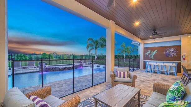 A covered outdoor area with wicker furniture, a pool, and a bar area. - Paradise at Bear's Den | 6-Bed Villa w/ Loft, Games Room, and Private Pool (Kissimmee)