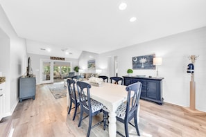 A spacious dining area with a large table and chairs, a dark blue cabinet, and a ceiling fan.