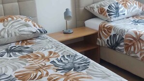 Ein Schlafzimmer mit zwei Betten, jeweils mit einem blumengemusterten Überwurf, einem Nachttisch mit Lampe und einem Holznachttisch.
