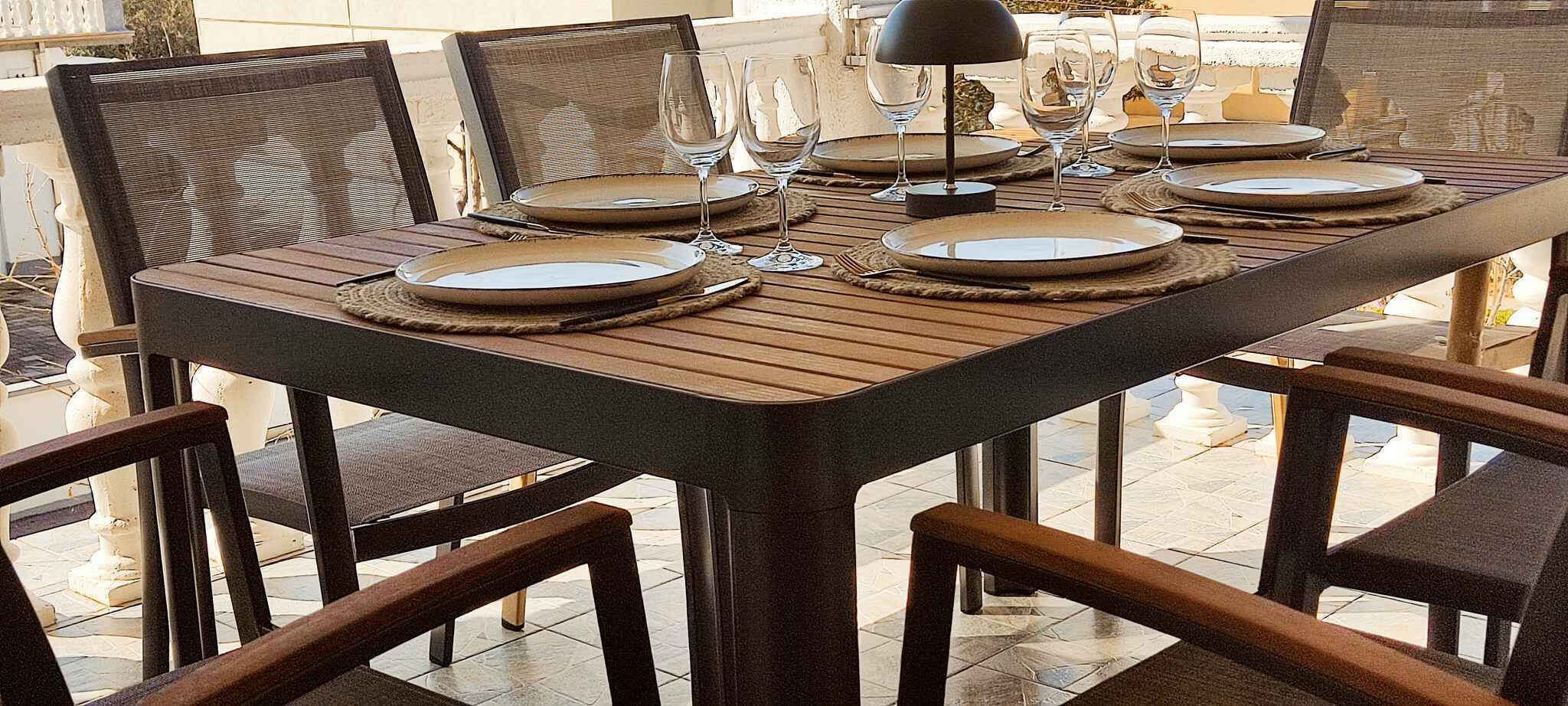 A dining table set with plates, glasses, and cutlery, surrounded by chairs.