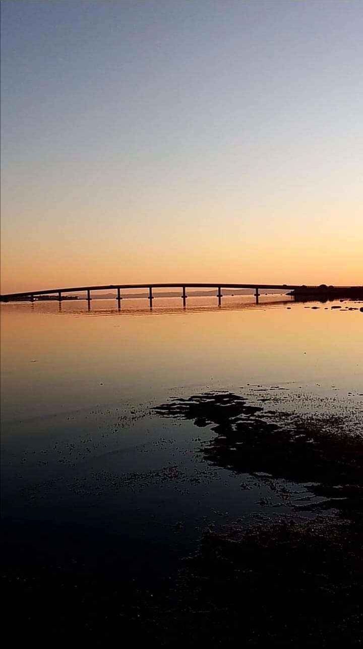 Eine Brücke über ruhigem Wasser bei Sonnenuntergang.