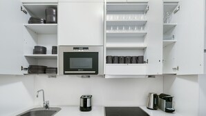 Een moderne keuken met witte kastjes, een inbouwoven, een spoelbak en een koffieapparaat.