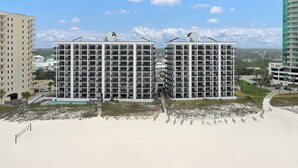 Un hotel frente a la playa con varios pisos, piscina y acceso directo a la playa.