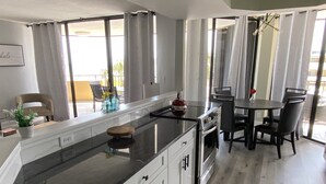 Een moderne keuken met een zwart aanrecht, witte kastjes en een eethoek met een tafel en stoelen.