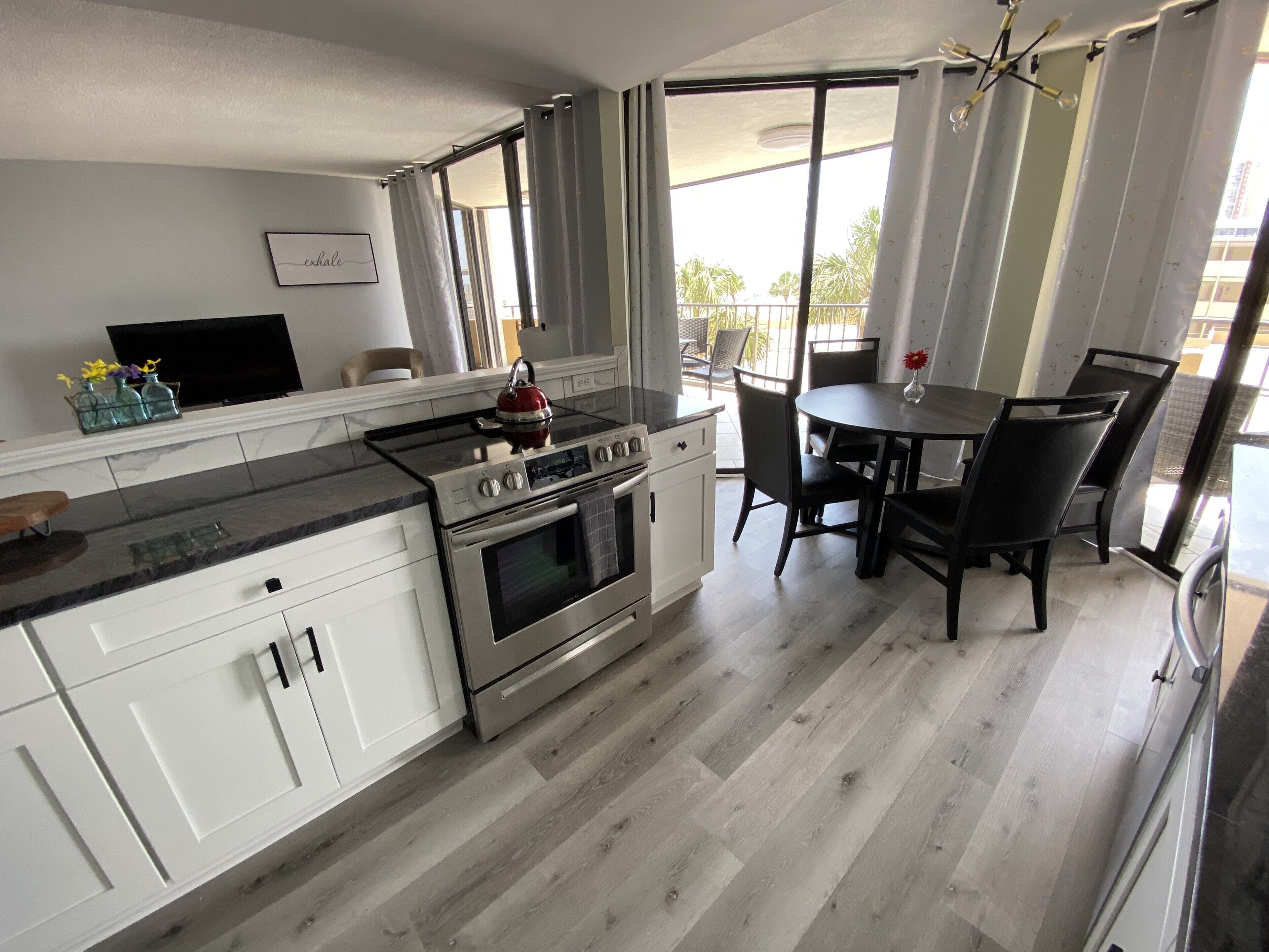 A modern kitchen with a stove, oven, and dining area with chairs and a table.
