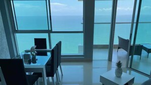 A modern living room with a large glass window overlooking the sea, a dining area with a table and chairs, and a minimalist white coffee table. - Luxurious & Spectacular View of Cartagena and the Caribbean Sea (Cartagena)