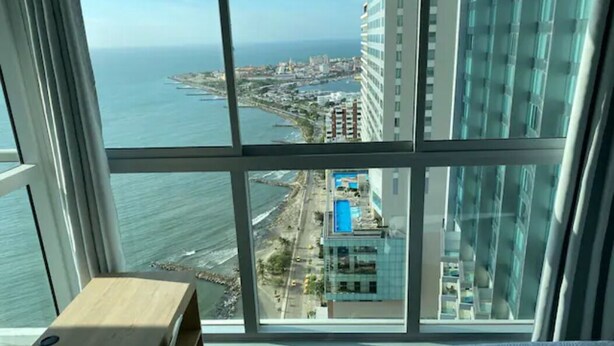 A room with a large window offering a view of the sea and a cityscape. - Luxurious & Spectacular View of Cartagena and the Caribbean Sea (Cartagena)