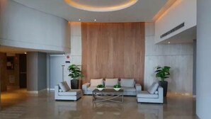 A spacious lobby with a modern design, featuring a large wooden panel wall, two white sofas with cushions, a central coffee table, and potted plants. - Luxurious & Spectacular View of Cartagena and the Caribbean Sea (Cartagena)