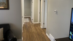 A hallway with wooden flooring, white walls, and a door leading to another room. - Lorie house Avon ohio (Avon)