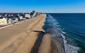 A coastal cityscape with a wide sandy beach and a clear blue sky. - Leave Car Behind! Walk to Beach, Boardwalk, Dining. (Ocean City)