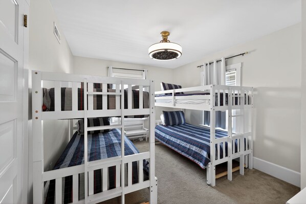 A room with bunk beds, a ceiling fan, and a door. - Leave Car Behind! Walk to Beach, Boardwalk, Dining. (Ocean City)