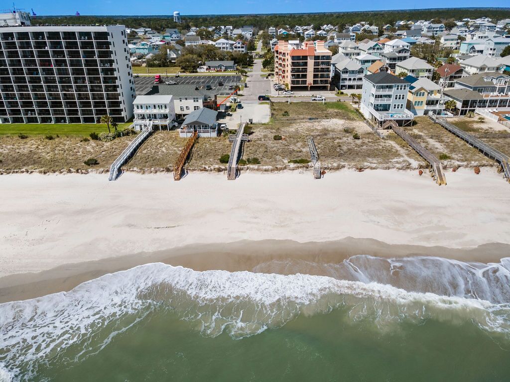 Ein Küstenhotel mit mehreren Gebäuden, einem Sandstrand und einem Steg.