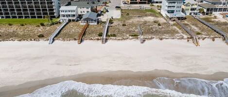 Ein Küstenhotel mit mehreren Gebäuden, einem Sandstrand und einem Steg.