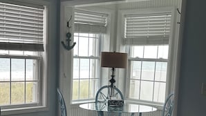 Un dormitorio con cama, una mesa redonda con sillas y ventanas grandes con persianas.