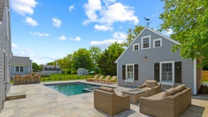 Un patio trasero con piscina, muebles de exterior y una pequeña construcción.