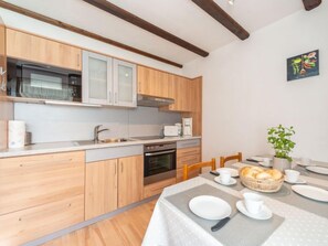 Eine moderne Küche mit Holzausstattung, einer Mikrowelle, einem Backofen und einem Essbereich mit Tisch für zwei Personen.
