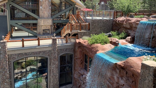 A hotel with a stone facade, multiple balconies, a pool with a waterfall, and outdoor seating areas. - ⛷️ SKI ONTO THE SLOPES • ⛳️ WALK ONTO THE LINKS • 🏔️ WESTGATE PARK CITY  (Park City)