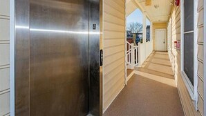 A corridor with a metallic elevator door, beige walls, and a carpeted floor.