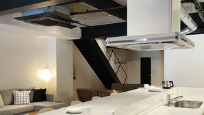 A modern kitchen with a central island, a built-in oven, and a large window. - bHotel Kaniwasou (Hatsukaichi)