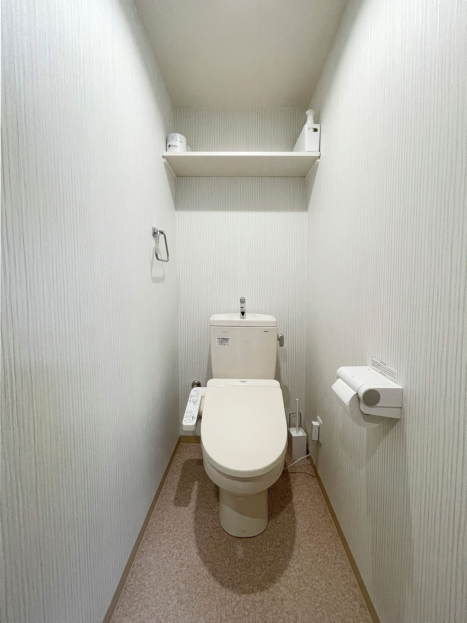 A small, compact bathroom with a toilet, a hand dryer, and a paper towel dispenser.