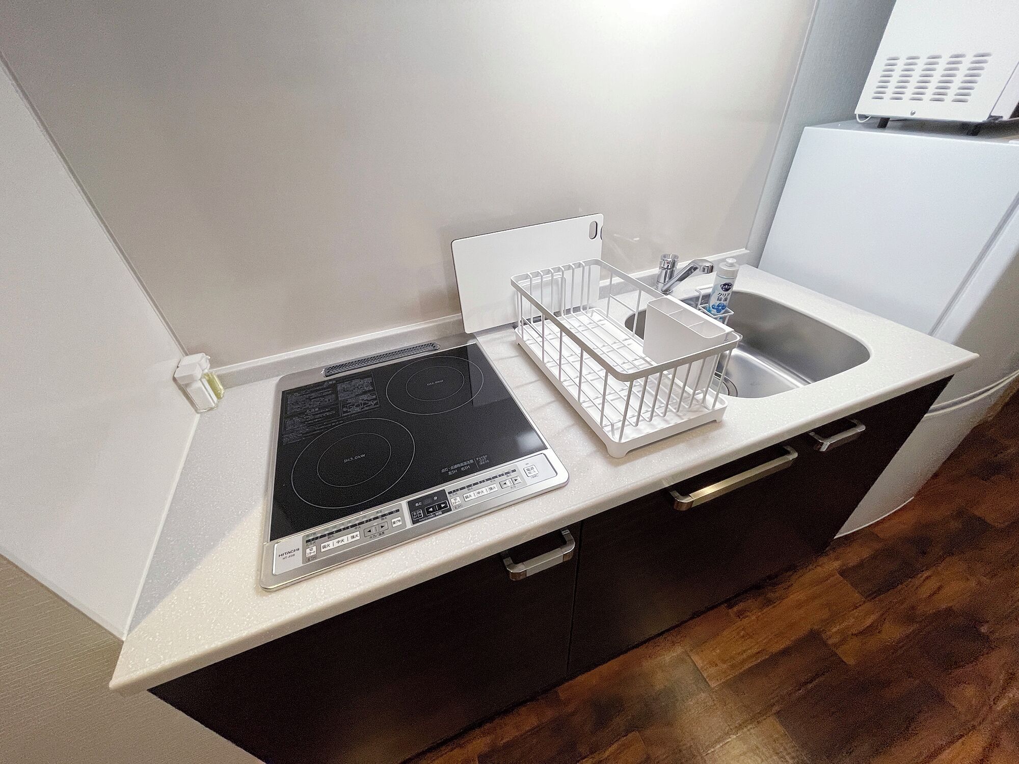A kitchen with a built-in induction cooktop, a white sink, and a white countertop.