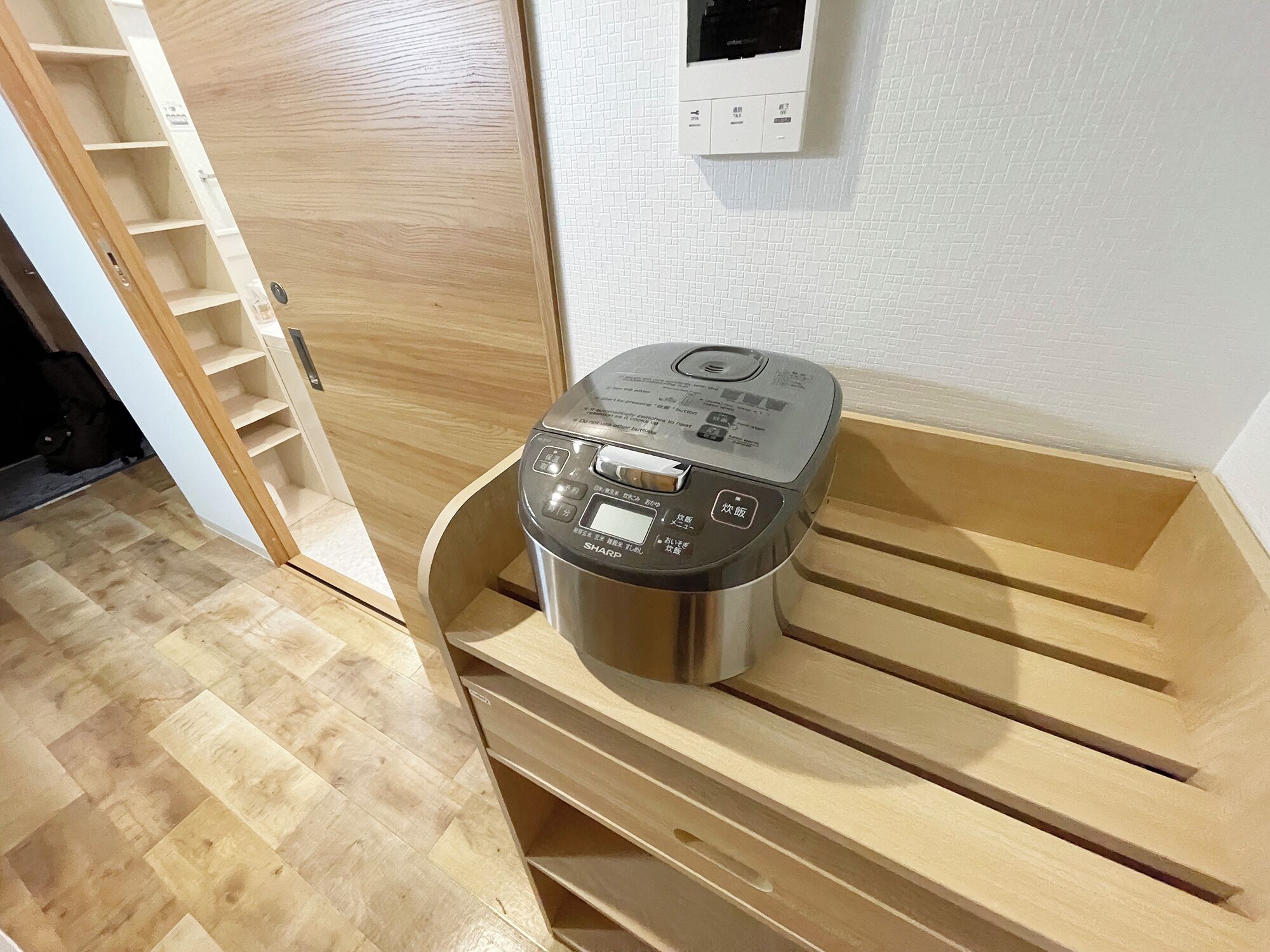 A room with a wooden bench, a stainless steel appliance, and a white tiled wall with a thermostat.