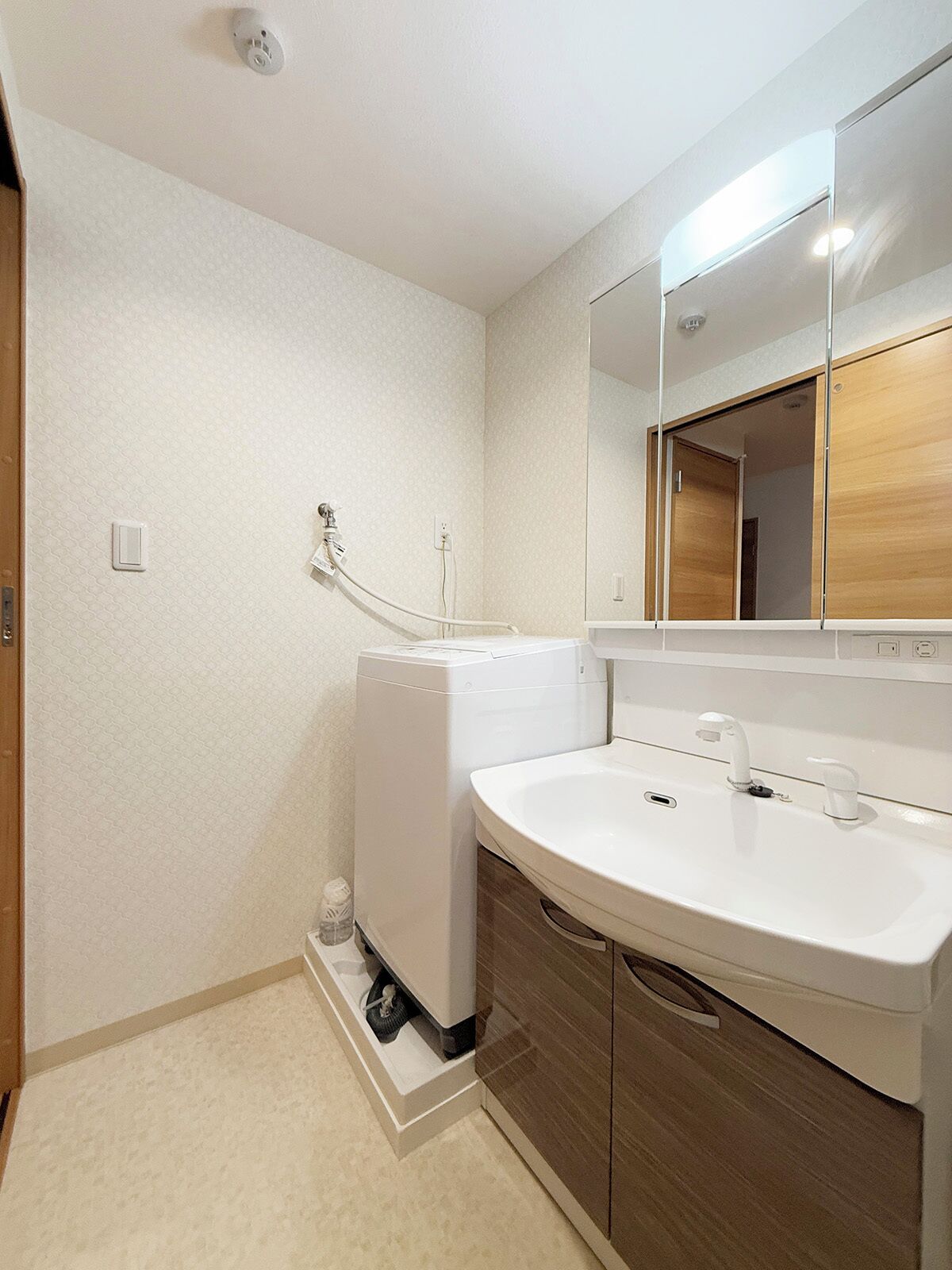 A modern bathroom with a white sink, wooden cabinets, and a large mirror.