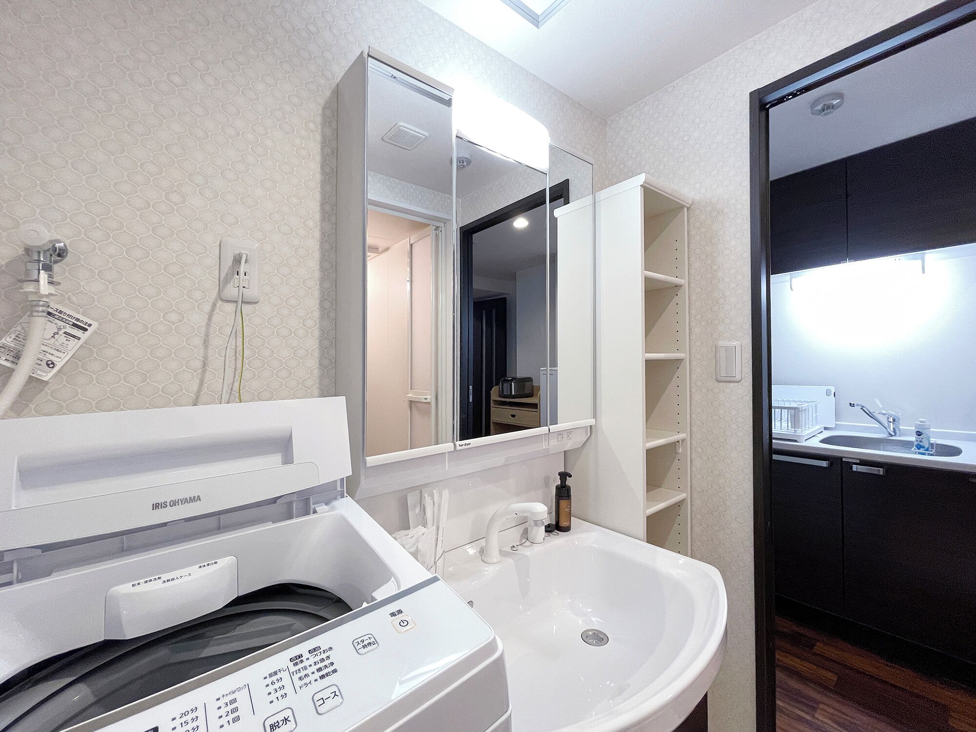 A modern bathroom with a built-in washing machine, a sink, and a mirror.