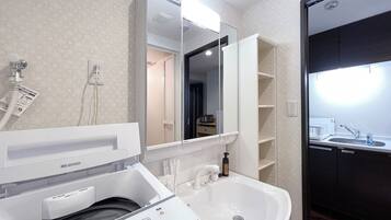 A modern bathroom with a built-in washing machine, a sink, and a mirror.