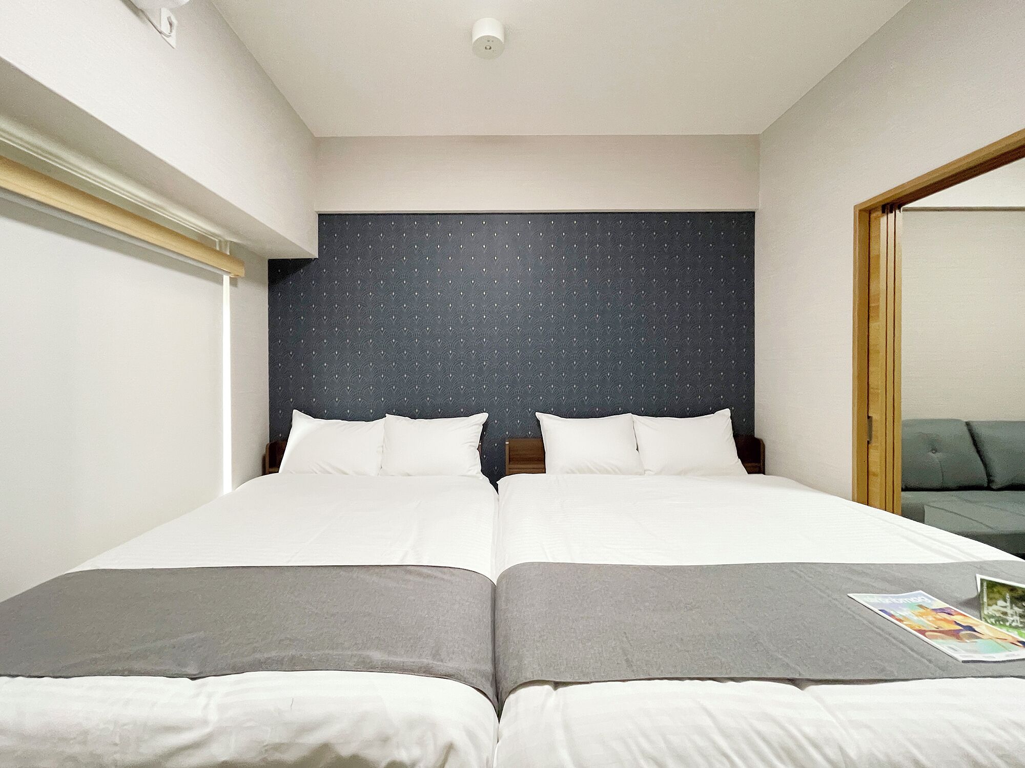 Une chambre d’hôtel avec deux lits, une tête de lit sombre et un grand miroir sur un des murs.