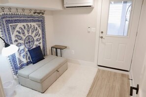 A room with a sofa, a patterned tapestry, a small table, and a door with a window. - Beautiful & Modern-near Subway Parking! (Washington)