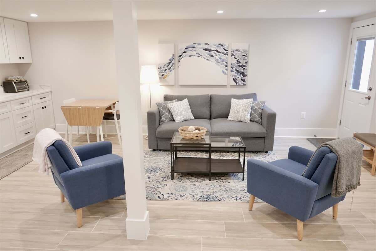 A living room with a grey sofa, two blue armchairs, a coffee table, and a modern abstract painting on the wall.