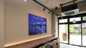 Un intérieur moderne avec un banc en bois, une œuvre d'art en verre bleu fixée au mur et une grande fenêtre avec un panneau indiquant la sortie.