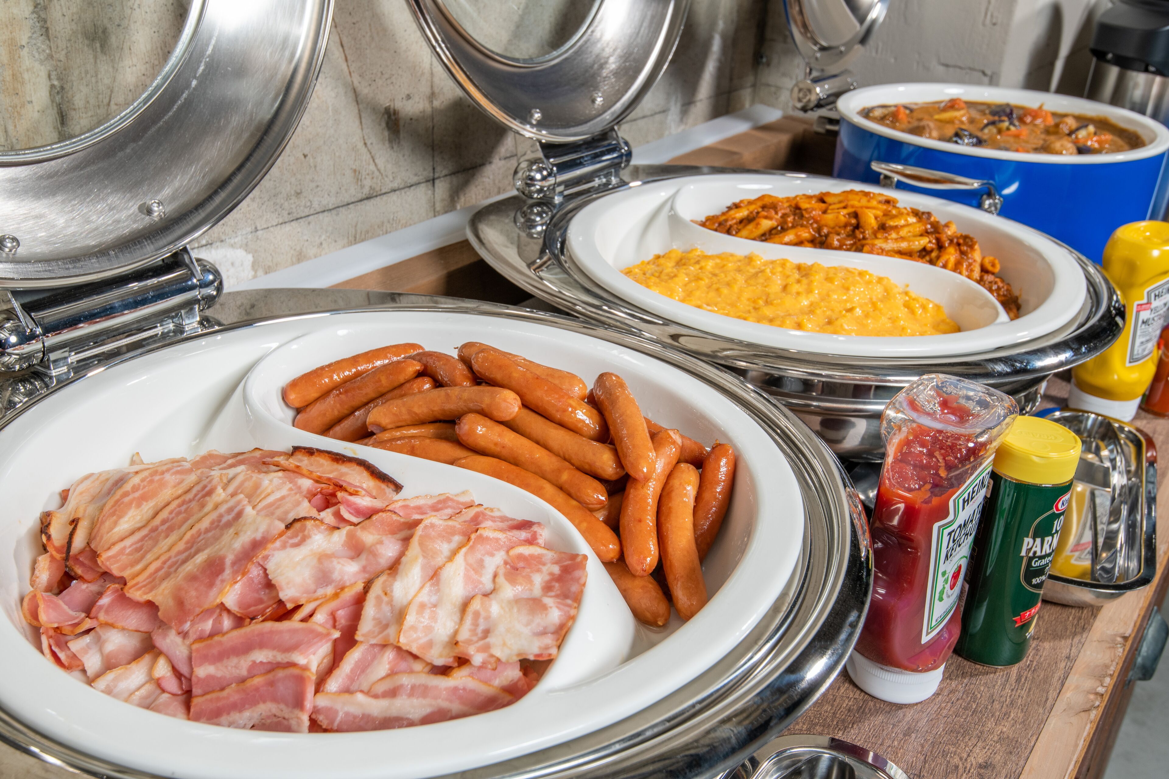 A buffet with various dishes including sausages, bacon, and casseroles.