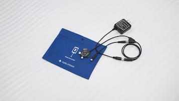 Un tapis bleu sur lequel reposent un câble pour appareil mobile et un chargeur USB, le tout posé sur une surface blanche.