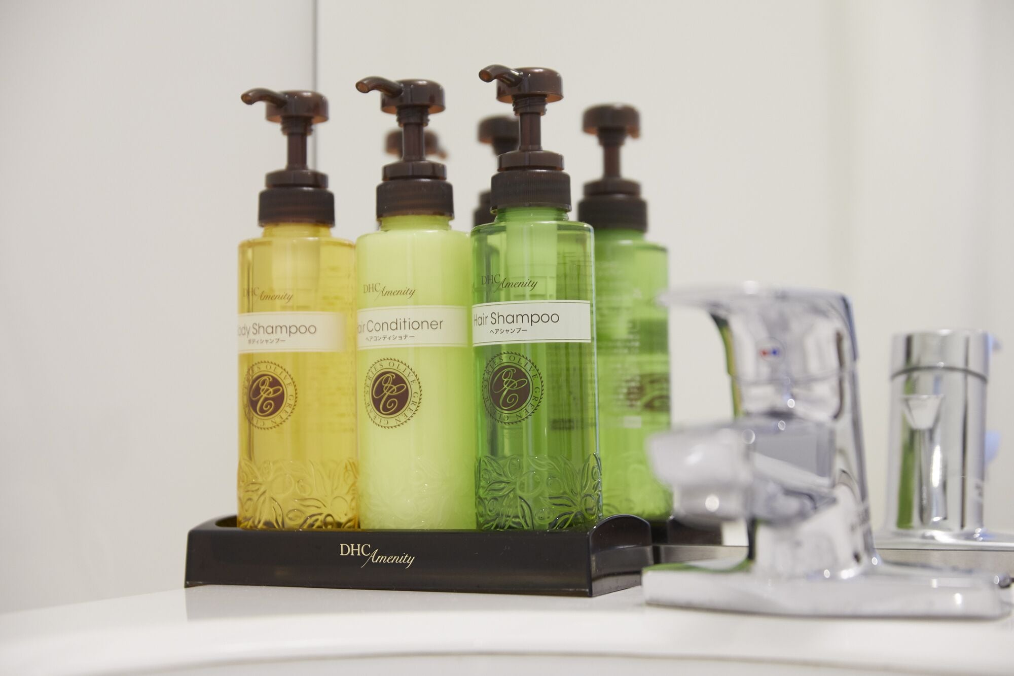 Un baño con lavamanos, espejo y set de artículos de tocador que incluye champú, acondicionador y gel de ducha.