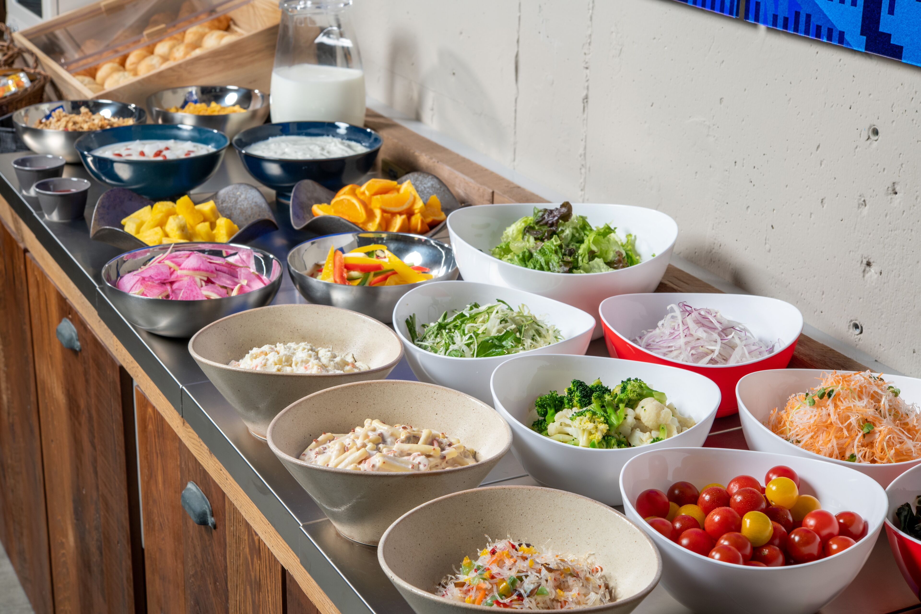 Buffet com diversos alimentos, incluindo saladas, frutas e massas.