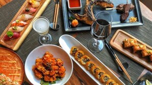 Une variété de plats, notamment des sushis, du poisson grillé et des nouilles, servis dans de nombreuses assiettes et sur des plateaux.