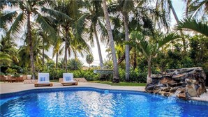Une piscine avec des chaises longues et des palmiers.